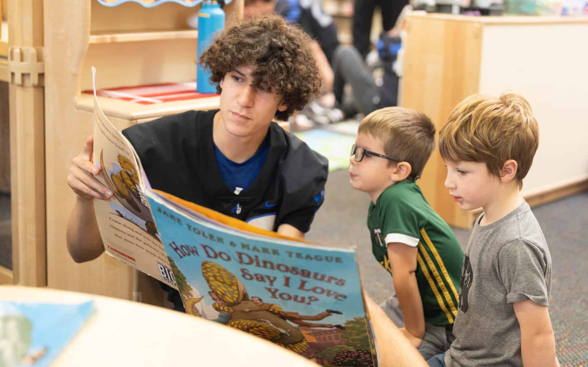 Early learning school students learning from high school student while reading